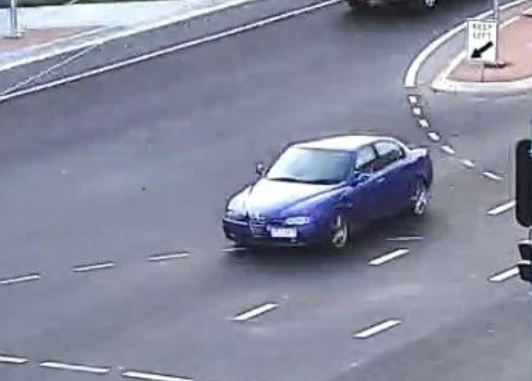 Uma câmera de trânsito captura um Alfa Romeo azul passando por um cruzamento.