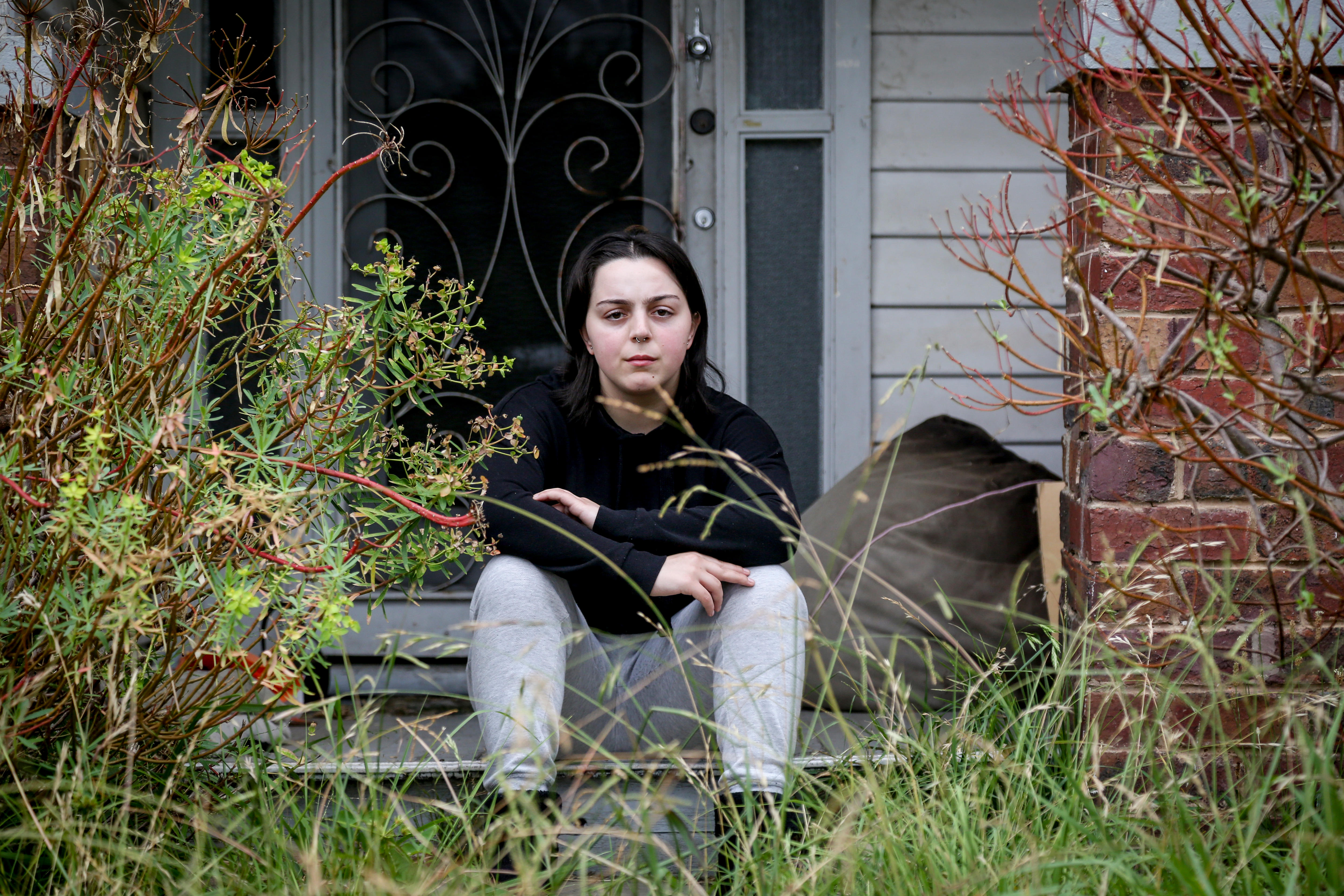 A woman sits on the front step of a house looking at the camera