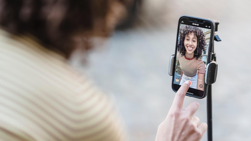 A woman looking at her image in her phone, in an article about how social media beauty filters affect women.