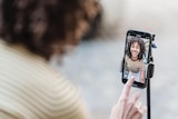 A woman looking at her image in her phone, in an article about how social media beauty filters affect women.