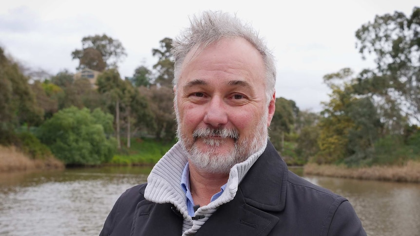 Yarra Riverkeeper Andrew Kelly stands with the river, banks and trees in the background