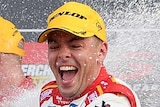 A SuperCars driver smiles as he sprays champagne over the crowd following his Bathurst 1000 win.