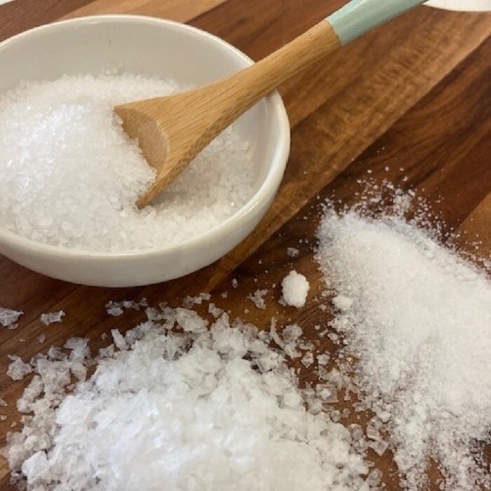 Three different types of salt sprinkled on a wooden board