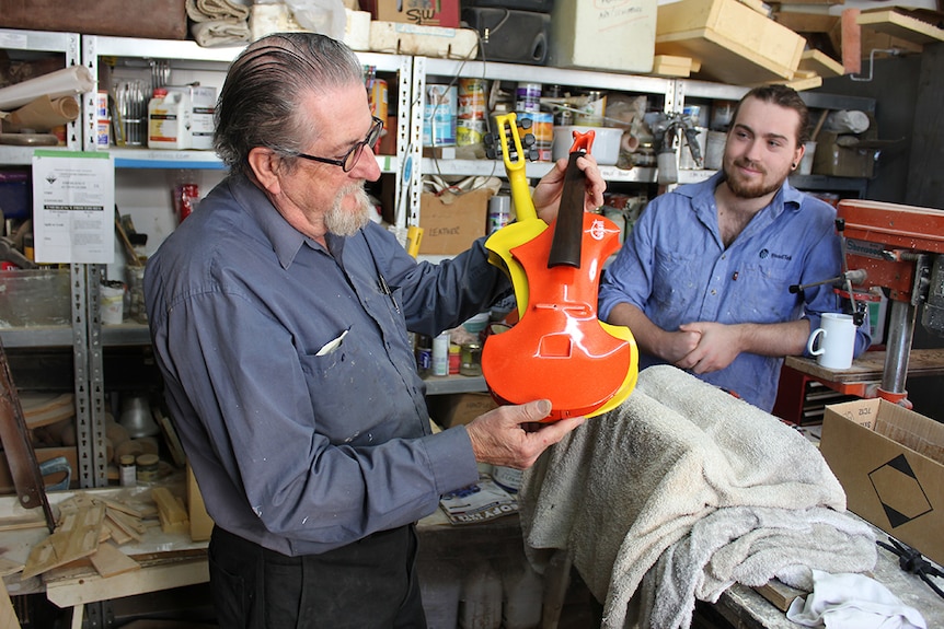 A luthier holds an instrument in his workshop