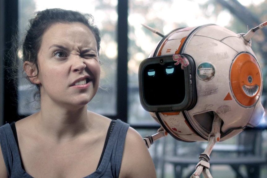 A young woman makes a funny face next to a robot