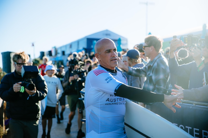Surfer Kelly Slater high fives a fan as he walks through the crowd at the Margaret River Pro.