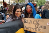 Two young women hold a placard saying Black Lives Matter