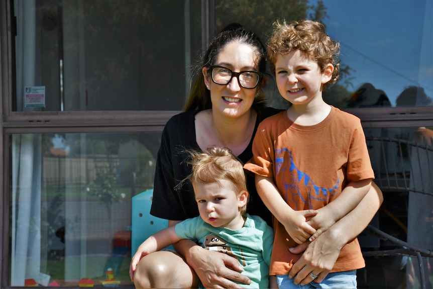 A young lady and her two children smile for the camera.