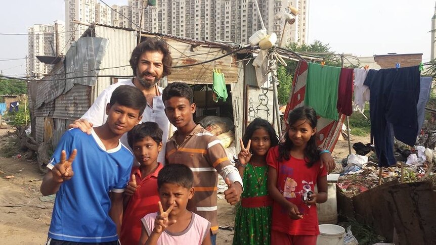 Jorge Invernon stands with young Indians in a slum.