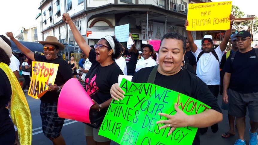 A stop Adani protest in Fiji held in 2017. They are marching through town, chanting and holding posters.