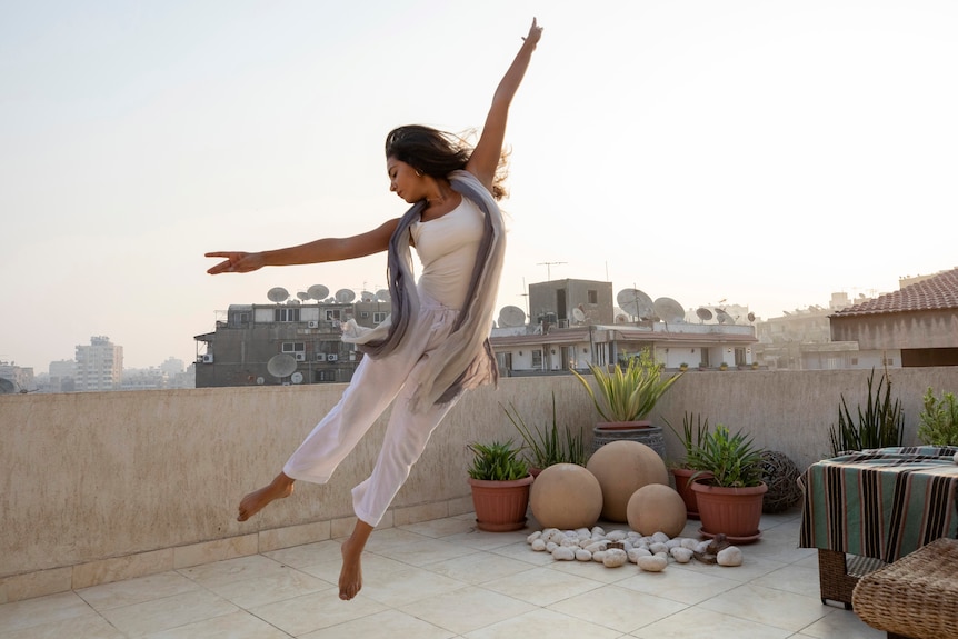 Woman dances on the rooftop of her home in Cairo, Egypt.