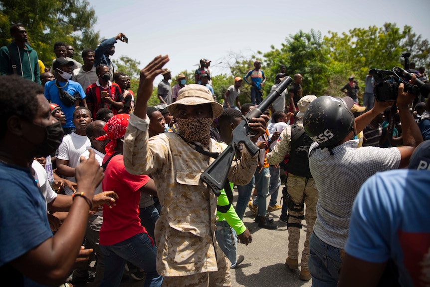 Police stand amid a crowd protesting against the assassination of Haitian President Jovenel Moïse