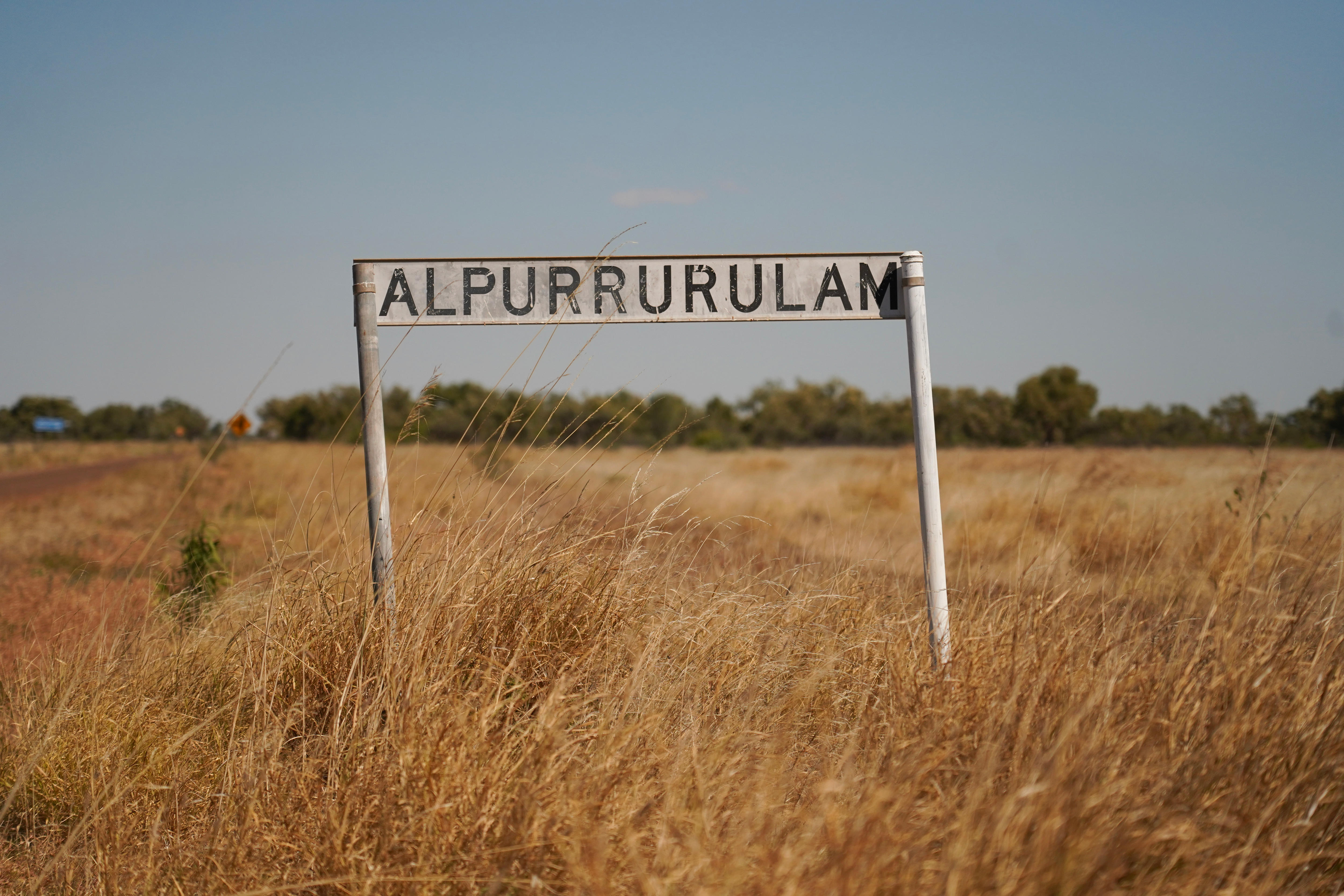 Street sign surrounded by long grass saying Alpurrurulam
