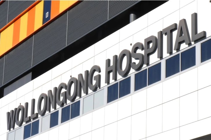 The front of a building with a sign pointing to Wollongong Hospital