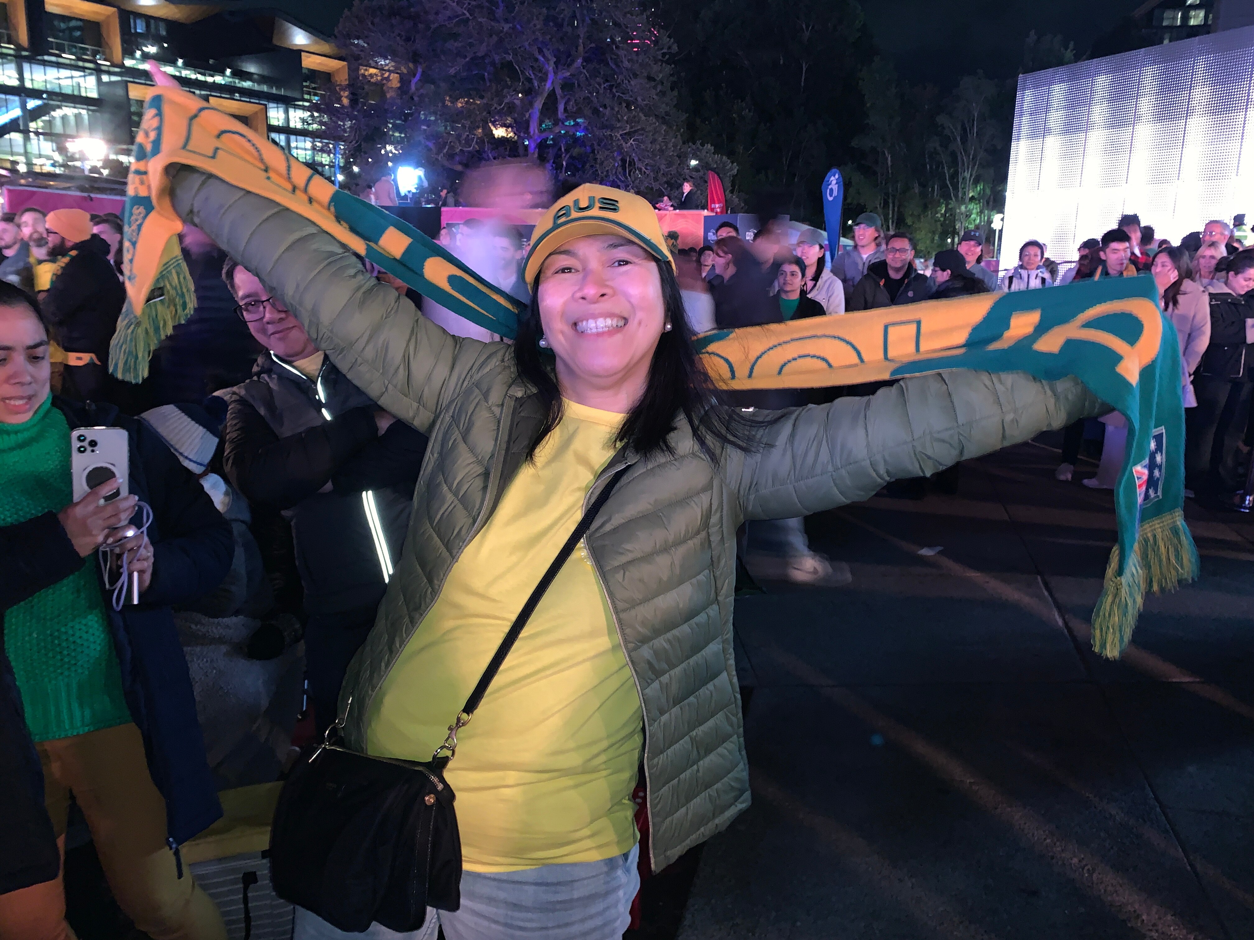 a woman holding up a matildas scarf