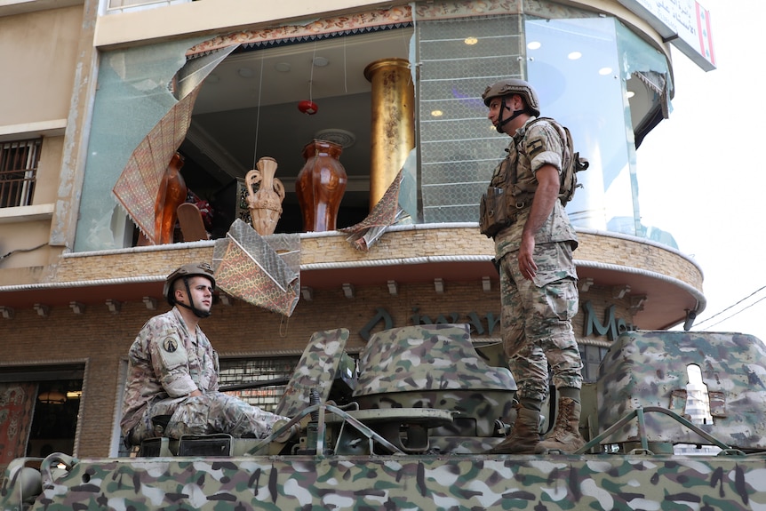 Two Lebanese Army soldiers stand on a street lined with rubble after a protest became violent in Beirut.