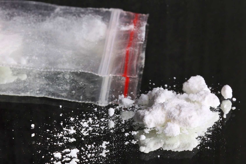 White power drug, sprinkled on reflective surface, with ziplock plastic bag.