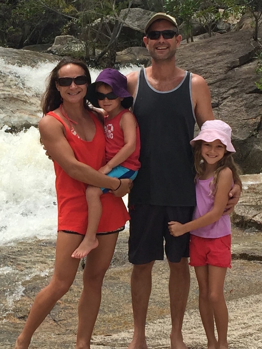 Family of four standing together in front of small waterfall