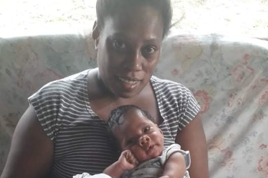 Woman holds small baby on couch.