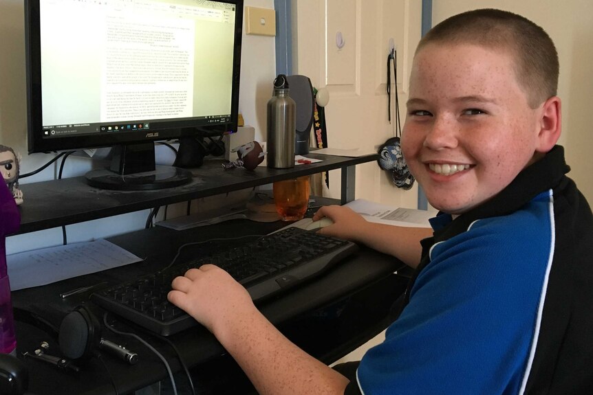 James Reid sits at a computer wearing his school uniform