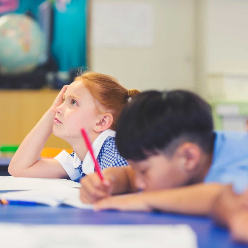 child looking tired in classroom listening to teacher