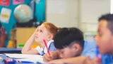 child looking tired in classroom listening to teacher