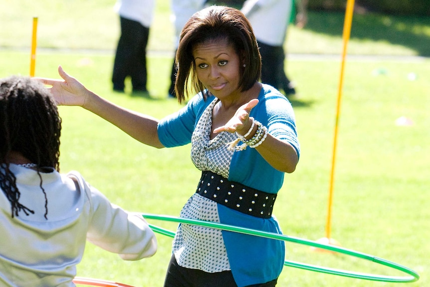 Michelle Obama tries to hula hoop with children at the White House Healthy Kids Fair on the South Lawn