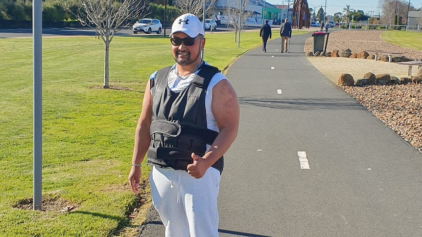 A man wearing a grey heavy vest and white pants on a walking track