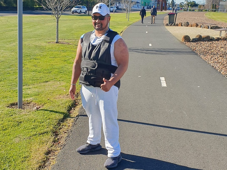 A man wearing a grey heavy vest and white pants on a walking track