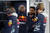 Daniel Ricciardo wearing his Red Bull uniform speaking with team officials at British Grand Prix.