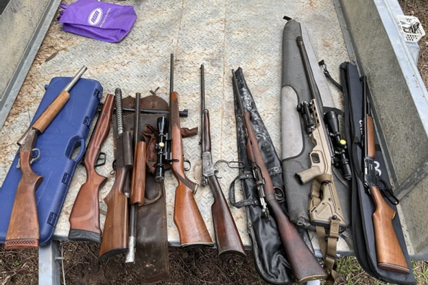 several large rifles and guns laid out on a table