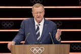 Australian Olympic Committee boss John Coates stands at a podium with the Olympic rings logo