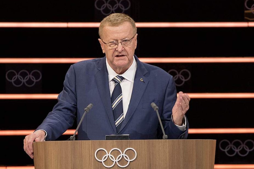 Australian Olympic Committee boss John Coates stands at a podium with the Olympic rings logo