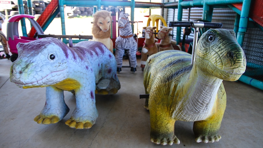 Dinosaur rides in the foreground with other animal rides in the background.