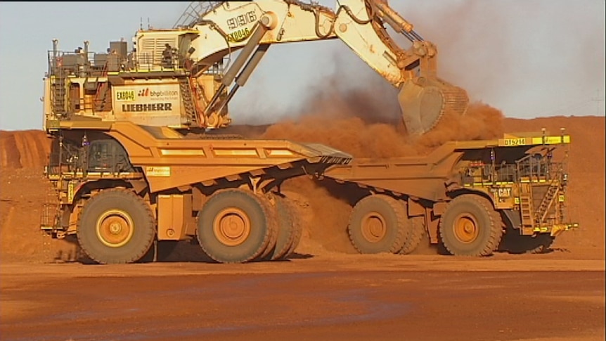 A mining digger loads driverless trucks with dirt