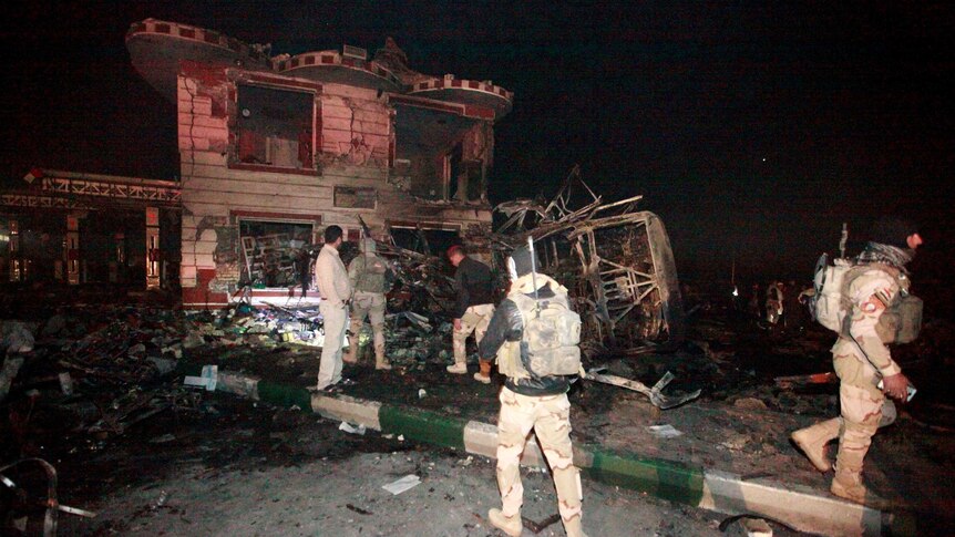 Iraqi security forces gather at the site of a suicide truck bomb attack.