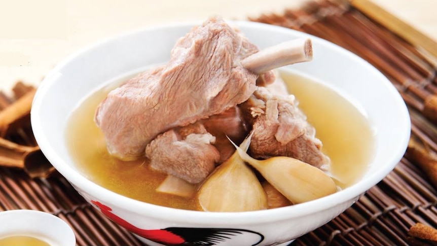 Soup with pork bones and shallots in it on a straw mat