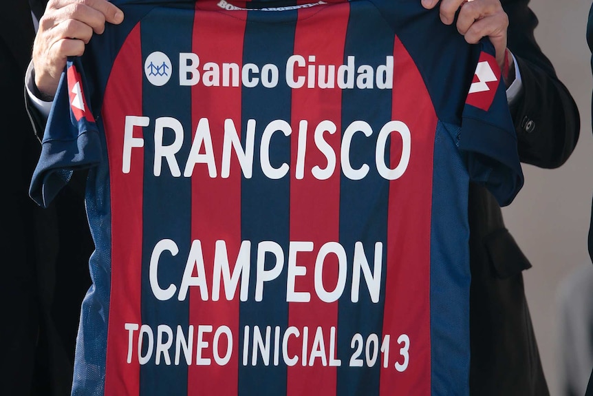 A member of Argentine soccer team San Lorenzo holds the navy and red jersey which reads "Franciso Campeon"