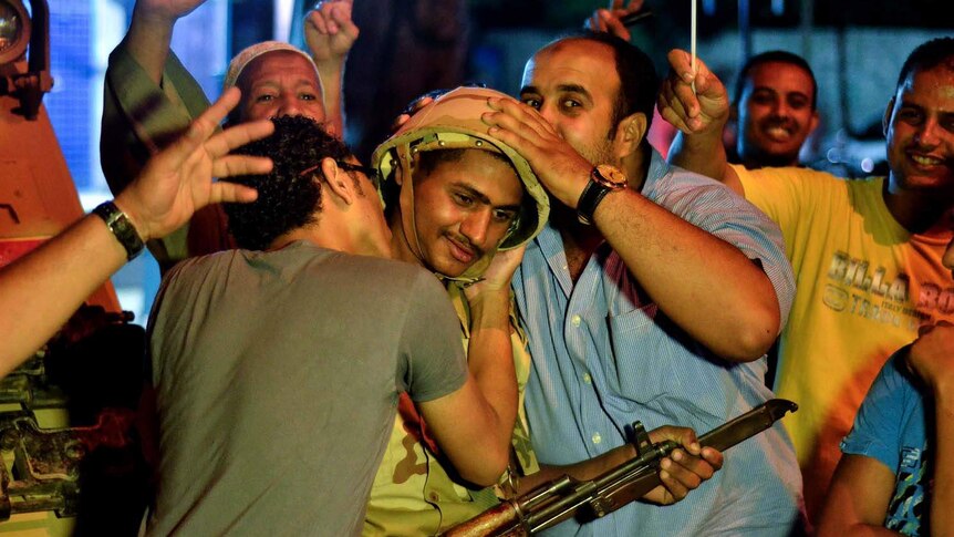 Egyptians in Cairo hug and kiss a soldier
