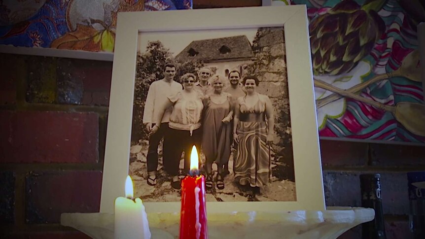 Two candles are lit in front of a photograph of the Menke family