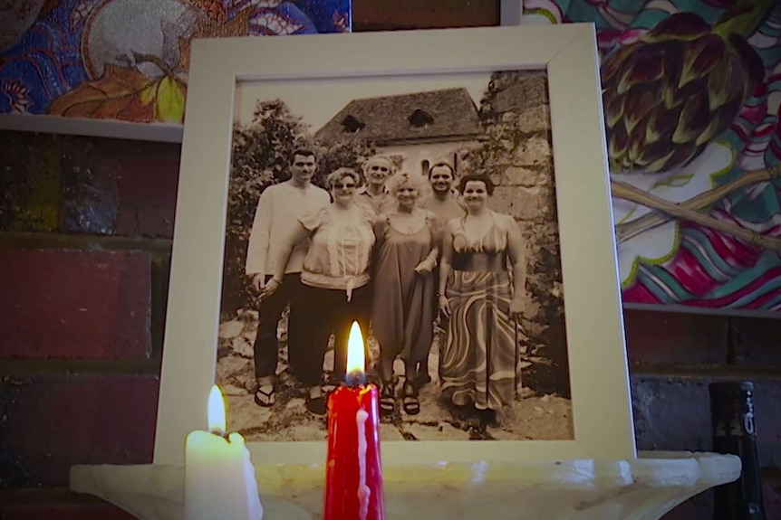 Two candles are lit in front of a photograph of the Menke family