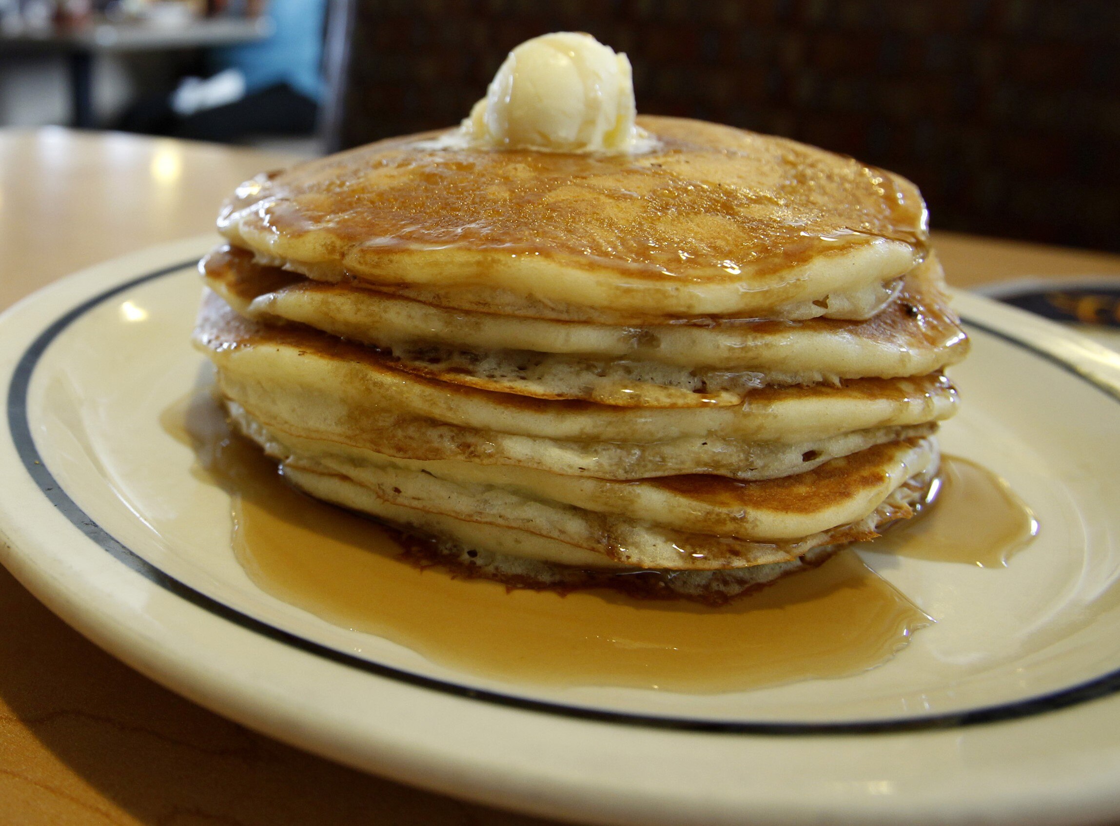A stack of four pancakes on a plate with ice cream and syrup 