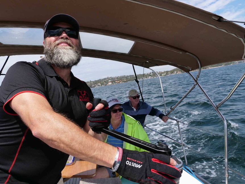 Sailor Adrian Whitby trims the sails on a winch on Sydney Harbour.