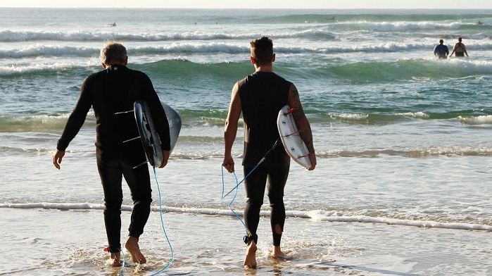 two me holding surfboards at the water's edge