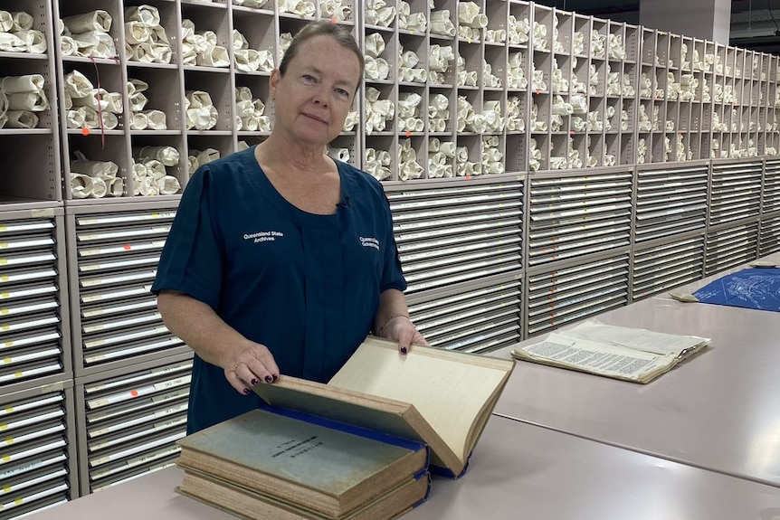 Queensland State Archives senior archivist Julanne Neal with some book items stored at the facility.