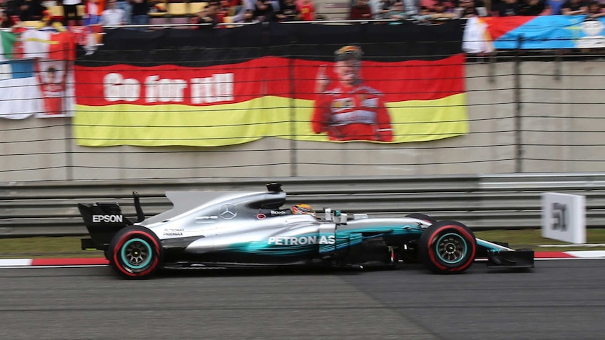 Mercedes driver Lewis Hamilton drives past a banner in qualifying at the Chinese F1 grand prix.