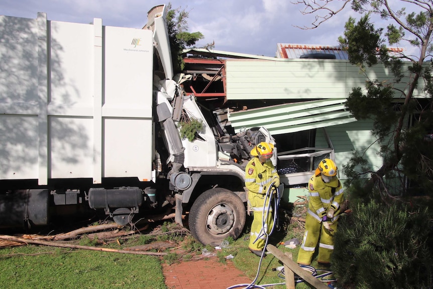 Firefighters in front of a rubbish truck with the cab crashed into the wall of a primary school classroom.