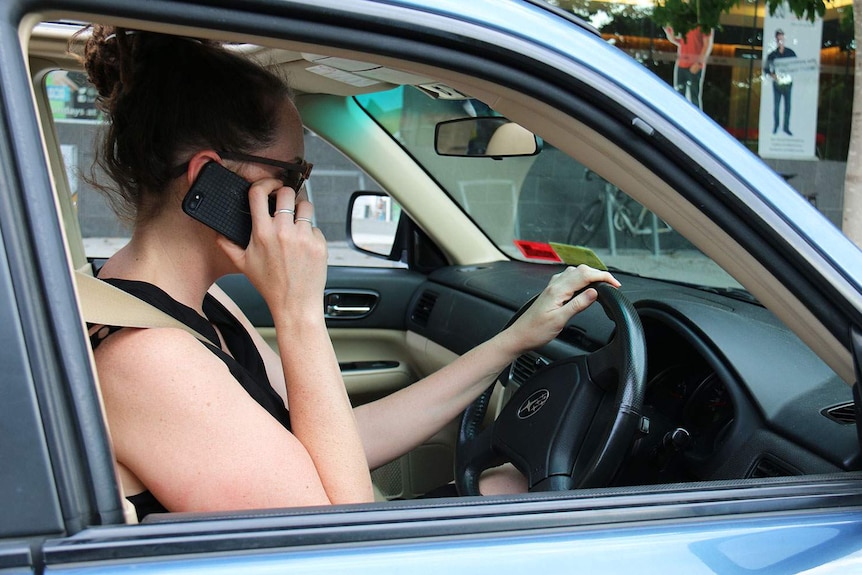 A woman has her phone to her ear in her car.