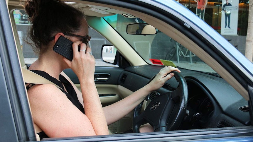 A woman has her phone to her ear in her car.