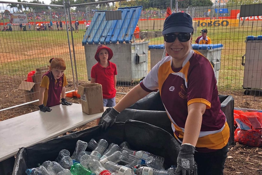 School students and a parent wearing gloves at the Townsville 400 beside a large bale of plastic bottles.